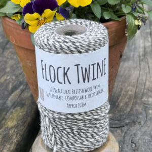 Image of a spool of flock twine in the garden with a pot of pansies